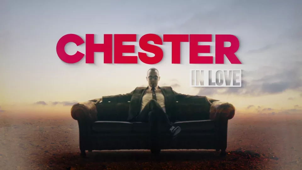 Título CHESTER IN LOVE sobre hombre en traje sentado en sofá en desierto.